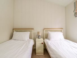 A bedroom with two single beds with white bedding separated by a nightstand with a lamp at Lakeview Lodge in Forton near Garstang