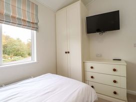 A bedroom with a bed a wardrobe a chest of drawers and a wall mounted TV at Lakeview Lodge in Forton near Garstang