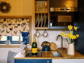A kitchen counter with a bottle of champagne glasses kettle flowers and a microwave at Lillies Shepherds Hut at Shepherds Lodge Bottesford near Redmile and Vale of Belvoir