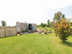 A wooden shepherds hut with open blue doors and outdoor seating area on a grassy lawn at Lillies Shepherds Hut at Shepherds Lodge Bottesford near Redmile and Vale of Belvoir