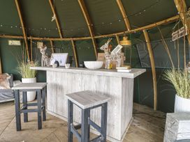 A wooden bar with stools inside a tent with decorative items and plants at Lillie's Shepherds Hut at Shepherds Lodge Bottesford near Redmile and Vale of Belvoir