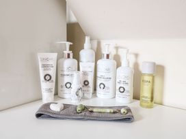 A collection of skincare products including cleansing foam lotion cream and bath oil on a white surface at Lillies Shepherds Hut at Shepherds Lodge Bottesford near Redmile and Vale of Belvoir
