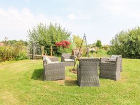 An outdoor seating area with five wicker chairs arranged around a fire pit and a wooden wheel in the background at Lillies Shepherds Hut at Shepherds Lodge in Bottesford near Redmile and Vale of Belvoir
