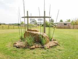 A grassy area with rocks and plants surrounded by wooden signs hanging from a wooden frame at Lillies Shepherds Hut at Shepherds Lodge in Bottesford near Redmile and Vale of Belvoir