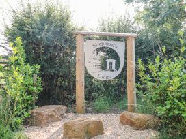 A wooden sign reading Shepherd's Lodge surrounded by bushes and rocks at Lillie's Shepherds Hut at Shepherds Lodge Bottesford near Redmile and Vale of Belvoir