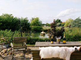 A garden with a table, chairs, and bottles near a water source at Lillie's Shepherds Hut at Shepherds Lodge Retreat and Wellness, Bottesford near Redmile and Vale of Belvoir