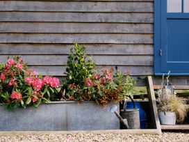 A wooden wall with flowers and a blue door at Lillie's Shepherds Hut at Shepherds Lodge Retreat and Wellness in Bottesford near Redmile and Vale of Belvoir