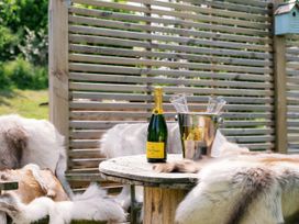 An outdoor seating area with a champagne bottle and glasses at Lillie's Shepherds Hut at Shepherds Lodge Retreat and Wellness Bottesford near Redmile and Vale of Belvoir