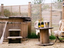 An outdoor area with a hot tub and champagne at Poppie's Shepherds Hut at Shepherds Lodge Retreat and Wellness Bottesford near Redmile and Vale of Belvoir