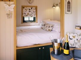 A bedroom with a bed and wine bottle at Poppie's Shepherds Hut at Shepherds Lodge Retreat and Wellness Bottesford near Redmile and Vale of Belvoir
