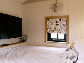 A bedroom with a television and curtain at Poppie's Shepherds Hut at Shepherds Lodge Retreat and Wellness in Bottesford near Redmile and Vale of Belvoir