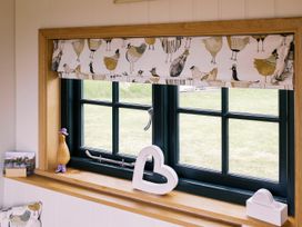 A window with a curtain and decorative items at Poppie's Shepherds Hut at Shepherds Lodge Retreat and Wellness Bottesford near Redmile and Vale of Belvoir