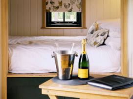 A bedroom with a bed, champagne on a table at Poppie's Shepherds Hut at Shepherds Lodge Retreat and Wellness near Bottesford