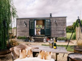 A sheep hut with a table and chairs outside at Poppie's Shepherds Hut at Shepherds Lodge Retreat and Wellness Bottesford near Redmile and Vale of Belvoir