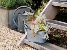 A plant pot and watering can on wooden stairs at Poppie's Shepherds Hut at Shepherds Lodge Retreat and Wellness Bottesford near Redmile and Vale of Belvoir