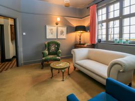 A living room with a white sofa green armchair and a small round table at The Gables in Spaxton near Nether Stowey