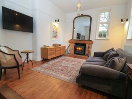 A living room with a fireplace a large mirror a sofa an armchair and a wall-mounted tv at The Gables in Spaxton near Nether Stowey