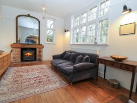 A living room with a fireplace a large mirror a sofa a wooden table and a patterned rug at The Gables in Spaxton near Nether Stowey