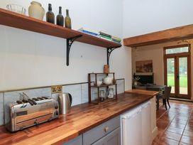 A kitchen counter with a toaster kettle and shelves with bottles and books at The Gables in Spaxton near Nether Stowey