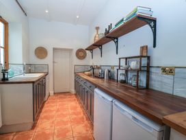 A kitchen with wooden countertops gray cabinets tile floor and open wooden shelves at The Gables in Spaxton near Nether Stowey