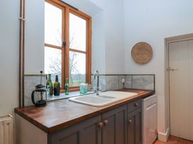 A kitchen sink with wooden countertop and bottles on windowsill at The Gables in Spaxton near Nether Stowey