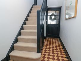 A staircase with beige carpet and a black door with a wreath at The Gables in Spaxton near Nether Stowey