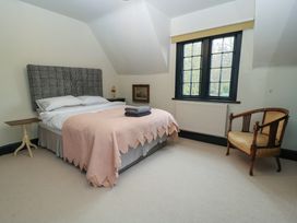 A bedroom with a bed covered by a pink quilt and folded towels a wooden chair and two small tables near a window at The Gables in Spaxton near Nether Stowey
