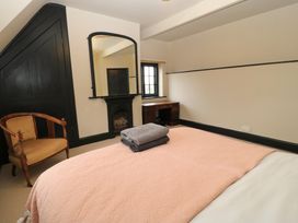 A bedroom with a bed covered by a pink blanket and folded towels on top with a wooden chair a fireplace with a mirror above it and a wooden desk under a window at The Gables in Spaxton near Nether Stowey
