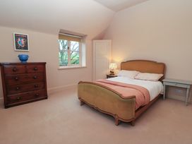A bedroom with a bed a wooden chest of drawers a window and a bedside table at The Gables in Spaxton near Nether Stowey