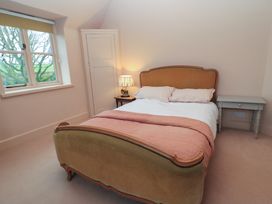 A bedroom with a bed a bedside table with a lamp a window and a small cabinet at The Gables in Spaxton near Nether Stowey