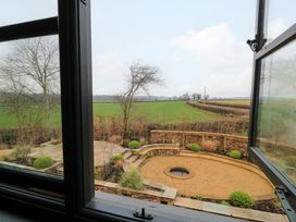 A garden with a circular gravel area and plants viewed through an open window at The Gables in Spaxton near Nether Stowey