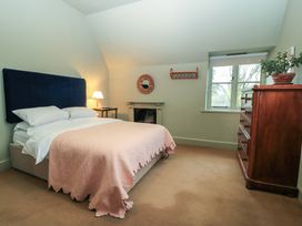 A bedroom with a bed a bedside table a lamp a wooden chest of drawers and a window at The Gables in Spaxton near Nether Stowey