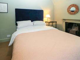 A bedroom with a bed with white pillows and pink blanket a bed lamp on a table a fireplace and a wall mirror at The Gables in Spaxton near Nether Stowey