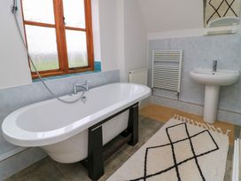 A bathroom with a bathtub a sink a towel radiator and a window at The Gables in Spaxton near Nether Stowey