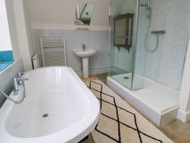 A bathroom with a bathtub a shower sink and a patterned rug at The Gables in Spaxton near Nether Stowey