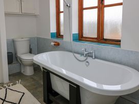 A bathroom with a freestanding bathtub a toilet and a window at The Gables in Spaxton near Nether Stowey