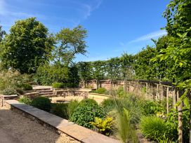 A garden with stone walls and benches surrounded by various plants and trees at The Gables in Spaxton near Nether Stowey