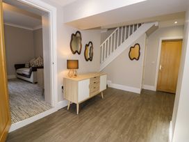 An entryway with a wooden cabinet and lamp next to a staircase and a view into a living room at Bwthyn Y Mor Tal-Y-Bont