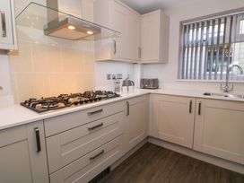 A kitchen with a gas stove a toaster a kettle and a sink with a window at Bwthyn Y Mor in Tal-Y-Bont