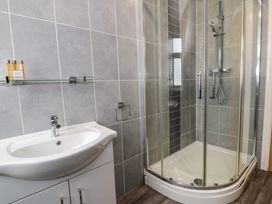 A bathroom with a white sink cabinet and a glass shower enclosure at Bwthyn Y Mor in Tal-Y-Bont