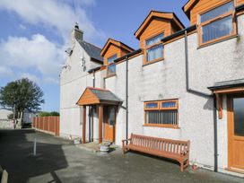 A house exterior with wooden framed windows and doors a bench and flower pots at Bwthyn Y Mor in Tal-Y-Bont
