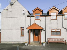 The front entrance of a house with a wooden door canopy two flower pots and a wooden bench at Bwthyn Y Mor in Tal-Y-Bont