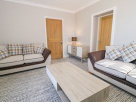 A living room with two sofas a wooden coffee table a sideboard with a lamp and two wooden doors at Bwthyn Y Mor in Tal-Y-Bont