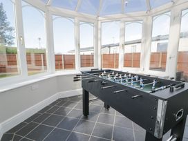 A foosball table in a room with windows and tiled floor at Bwthyn Y Mor in Tal Y Bont