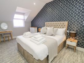 A bedroom with a double bed white bedding geometric wallpaper and a dressing table at Bwthyn Y Mor in Tal-Y-Bont