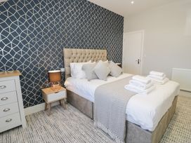 A bedroom with a bed pillows bedside tables lamps and folded towels at Bwthyn Y Mor in Tal-Y-Bont
