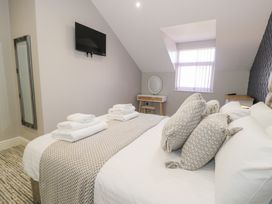 A bedroom with a bed with folded towels pillows a wall-mounted TV a mirror and a small desk at Bwthyn Y Mor in Tal-Y-Bont
