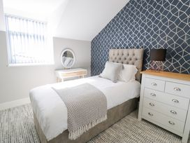 A bedroom with a single bed a bedside table with a lamp a wooden dresser and a vanity table with a round mirror at Bwthyn Y Mor in Tal-Y-Bont