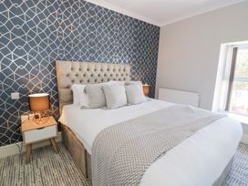 A bedroom with a double bed white bedding patterned pillows and blanket bedside tables lamps and a window at Bwthyn Y Mor in Tal-Y-Bont