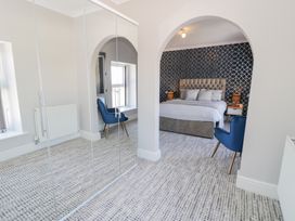 A bedroom with an archway leading to a bed with a blue and white patterned wall and blue chairs at Bwthyn Y Mor in Tal Y Bont